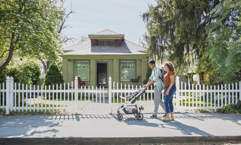 Family walking with stroller, house in background